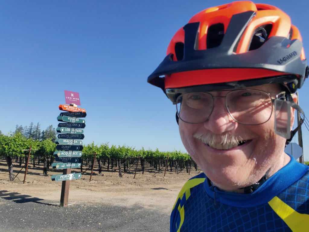 Host at a sign pointing to various wineries in Lodi, CA. 